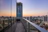 Curved balcony featuring wood-finish flooring, glass panel railings, and full-height exterior glass facade