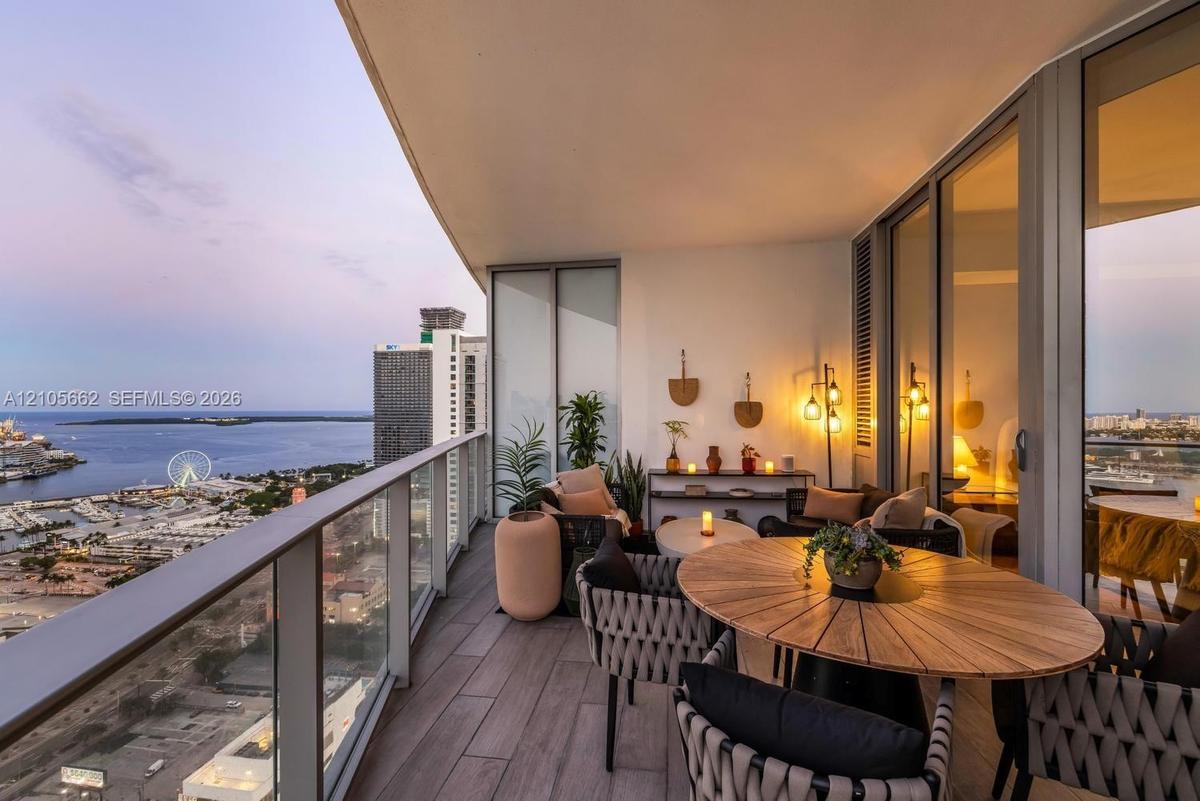 Covered balcony featuring wood-finish flooring, a glass panel railing, and expansive floor-to-ceiling windows