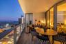 Covered balcony featuring wood-finish flooring, glass panel railings, floor-to-ceiling glass wall, and exterior lighting