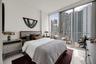 Floor-to-ceiling windows, polished light-toned tile flooring, and a private balcony featuring a glass-railing system