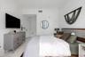 Neutral-toned room featuring large-format tile flooring, smooth white wall finishes, and a circular wall-mounted mirror