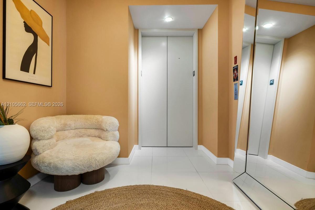 Private elevator access featuring smooth-finish metal doors, recessed ceiling lighting, and reflective wall-mounted mirror paneling