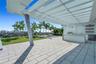 Outdoor terrace featuring a pergola with integrated string lighting, paved flooring, built-in kitchen counter, and open-air shelving