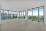 Floor-to-ceiling windows, wood-finish flooring, and an expansive balcony with glass railings
