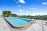 Rooftop swimming pool featuring a tiled deck, integrated metal safety railing, and encompassing urban and coastal scenery