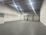 Industrial warehouse space featuring high ceilings, painted masonry walls, sealed concrete flooring, three metal roll-up doors, and overhead lighting