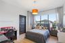 Room featuring wood-finish flooring, a large multi-pane window, and a dark-finished five-panel interior door with a brushed-metal lever handle