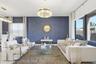 Textured blue accent wall featuring a contemporary crystal drum chandelier, large-format tile flooring, and oversized windows