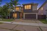 Modern two-story residence featuring a two-tone stucco facade, oversized paver driveway with integrated turf ribbons, multi-pane casement windows, and