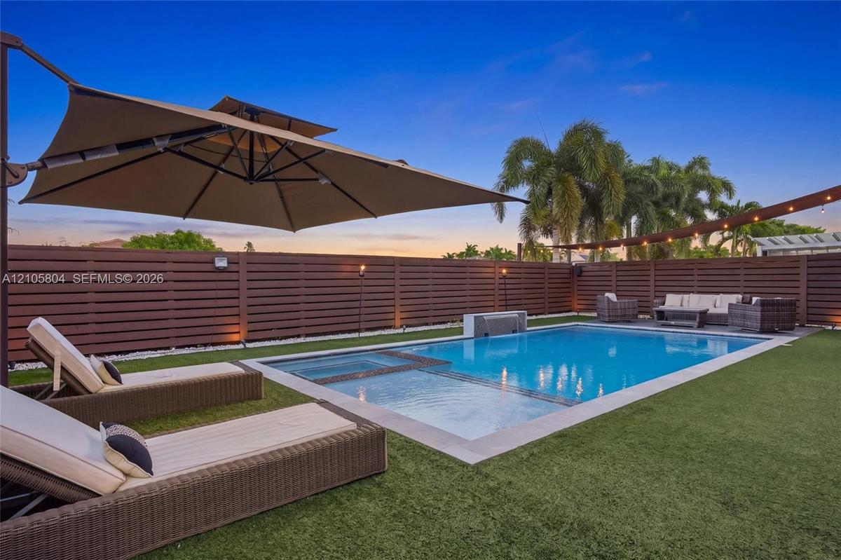 Private backyard featuring an inground swimming pool with an integrated spa, horizontal slat privacy fencing, a stone-finish water feature, and artifi