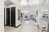 Polished porcelain tile flooring, dark-toned six-panel interior doors, and a multi-tiered crystal drum chandelier