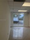 Interior space featuring large-format ceramic tile flooring, a drop ceiling with recessed lighting, and a full-height glass window
