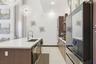 Kitchen featuring a waterfall-edge island with a quartz countertop, flat-panel cabinetry, high-ceiling drum pendant lighting, and stainless steel buil