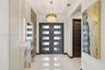 Entryway featuring a double-door entrance with frosted glass panels, tile flooring, a tiered crystal chandelier, and integrated wall paneling with rec