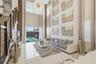 Double-height ceilings featuring floor-to-ceiling windows, polished tile flooring, a statement chandelier, and a staircase with a horizontal cable rai