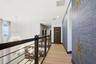 Upper-level walkway featuring wood-finish flooring, a contemporary horizontal cable railing system, textured blue wall covering, and recessed lighting