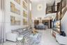 Double-height ceilings, porcelain tile flooring, kitchen featuring custom wood cabinetry and stainless steel appliances, tiered pendant lighting, and 
