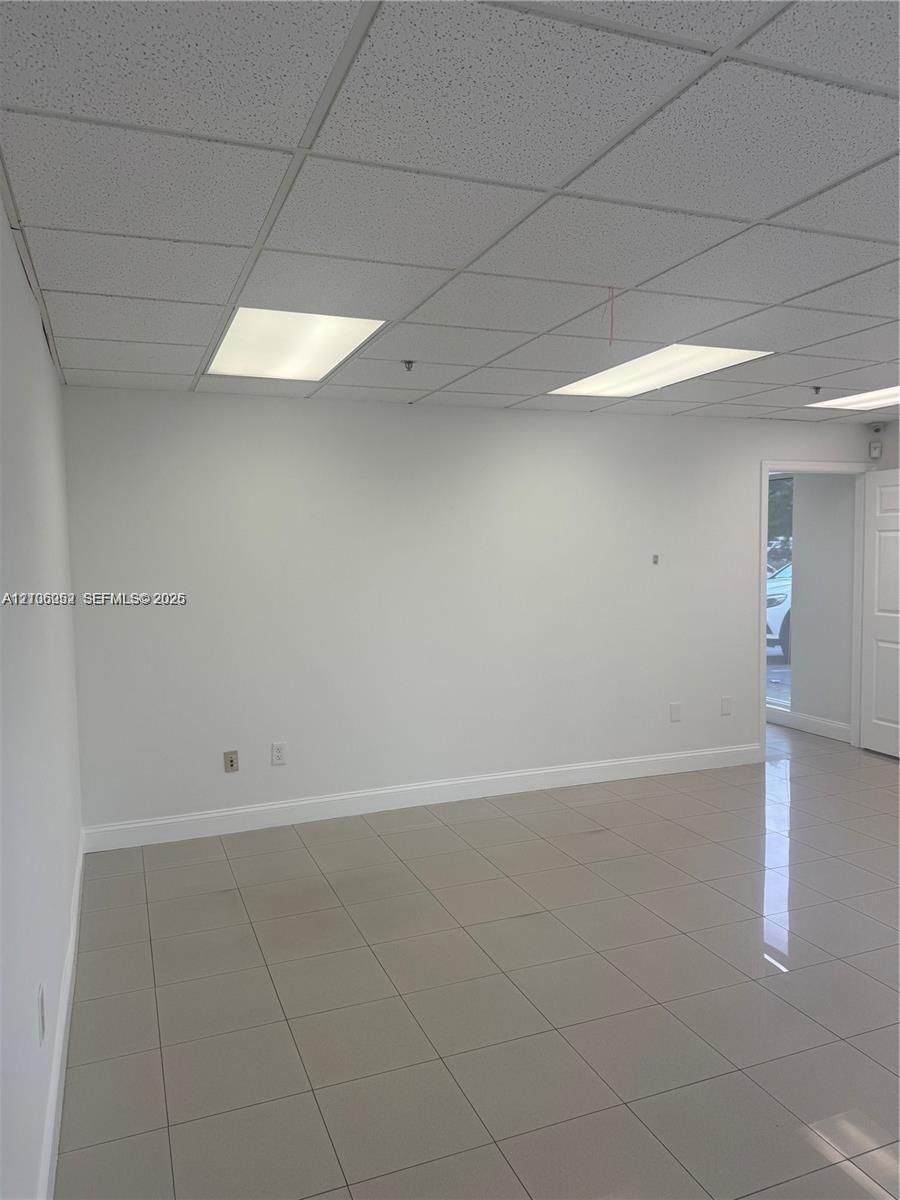 Neutral-toned ceramic tile flooring, drop ceiling with recessed rectangular lighting, and smooth-finished walls