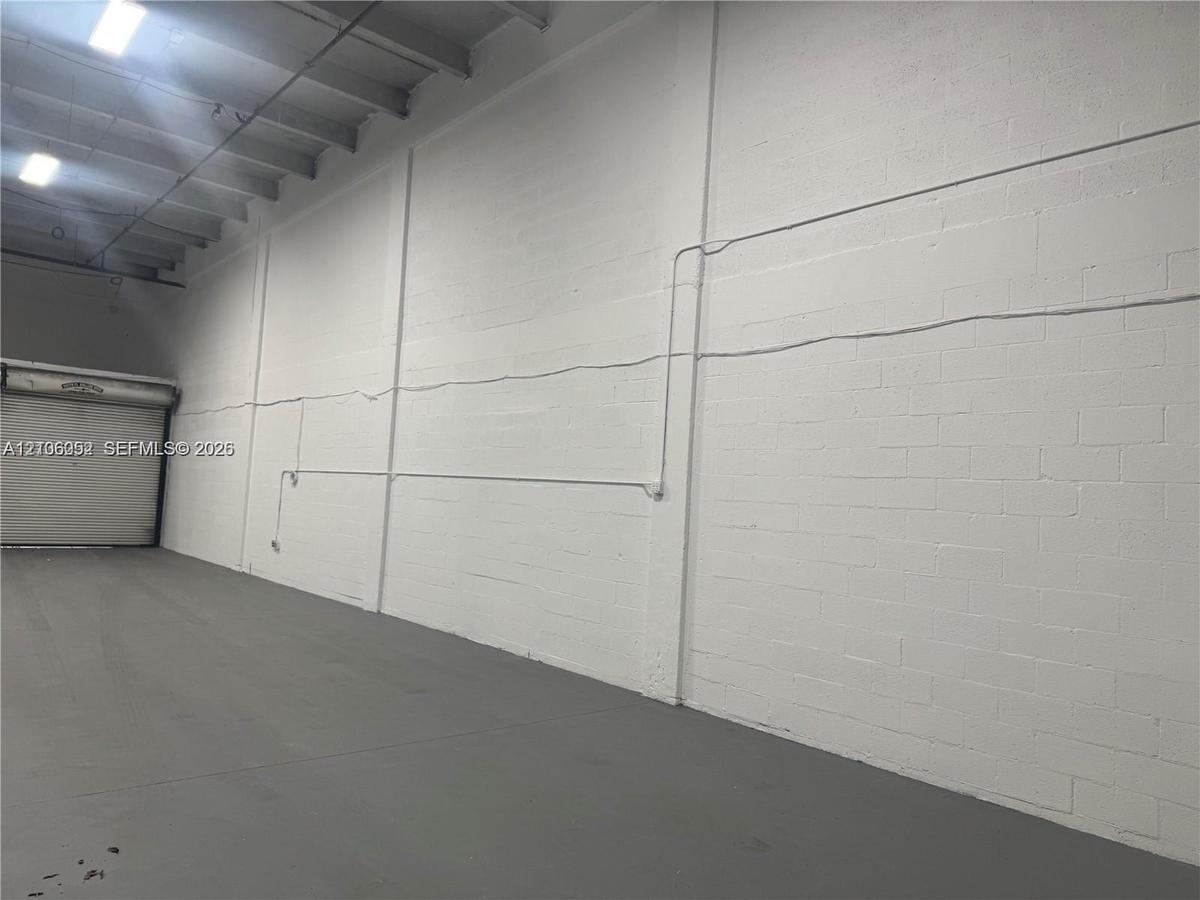 Industrial space featuring high ceilings, painted masonry walls, concrete flooring, and a metal roll-up overhead door