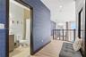 Textured blue wall covering, wood-finish flooring, metal railing with horizontal bars, and bathroom featuring a vanity with integrated sink