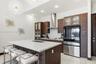 Kitchen featuring custom wood-finish cabinetry, a large central island with a quartz countertop, stainless steel appliances, a glass-tile backsplash, 