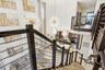 Double-height great room featuring multi-tiered sputnik-style chandeliers, metal cable stair railings, and an open-concept kitchen with built-in cabin