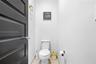 Powder room featuring a matte black paneled door, gold-tone hardware, and a high-profile toilet