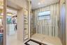 Walk-in shower with floor-to-ceiling tiled walls, glass enclosure, and rainfall showerhead, complemented by custom built-in cabinetry with integrated 