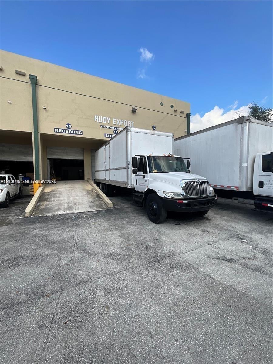 Industrial facility exterior featuring a concrete loading ramp, designated receiving and shipping bays, and paved exterior access