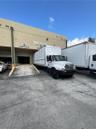 Industrial facility exterior featuring a concrete loading ramp, designated receiving and shipping bays, and paved exterior access