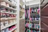 Custom walk-in closet featuring extensive built-in white shelving, integrated wood-finish cabinetry with drawers, and multi-tier hanging rods