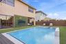 Backyard featuring an in-ground swimming pool with a built-in spa, horizontal wood-slat privacy fencing, artificial turf lawn, and an exterior wall fi