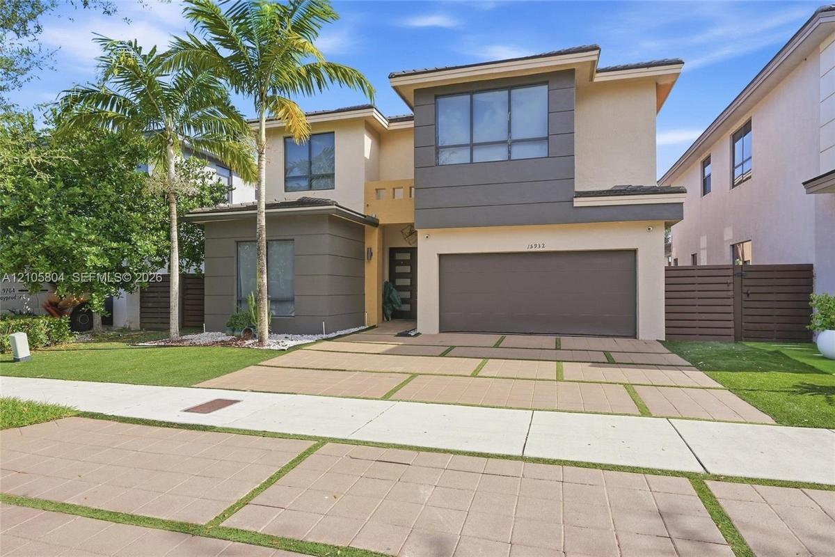 Contemporary two-story exterior featuring a multi-tone facade, large-format window groupings, two-car garage, and a geometric concrete paver driveway 