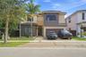 Two-story contemporary exterior featuring a concrete paver driveway, multi-toned stucco finish, large-format picture windows, and double-entry glass d