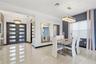 Dining area featuring large-format tile flooring, textured wall covering, custom linear crystal chandelier, and double front entry doors with frosted 