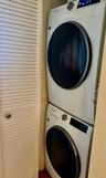 Stacked, front-load washer and dryer unit enclosed by white louvered doors