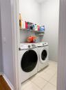 Laundry area featuring tile flooring and a wall-mounted wire shelving unit
