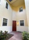 Entryway featuring a double-height ceiling, stucco exterior, paved walkway, and multiple multi-pane windows