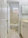 Bathroom featuring a vanity with a neutral-toned countertop, ceramic tile flooring, a tub-shower combination with ceramic wall tile, and a rectangular