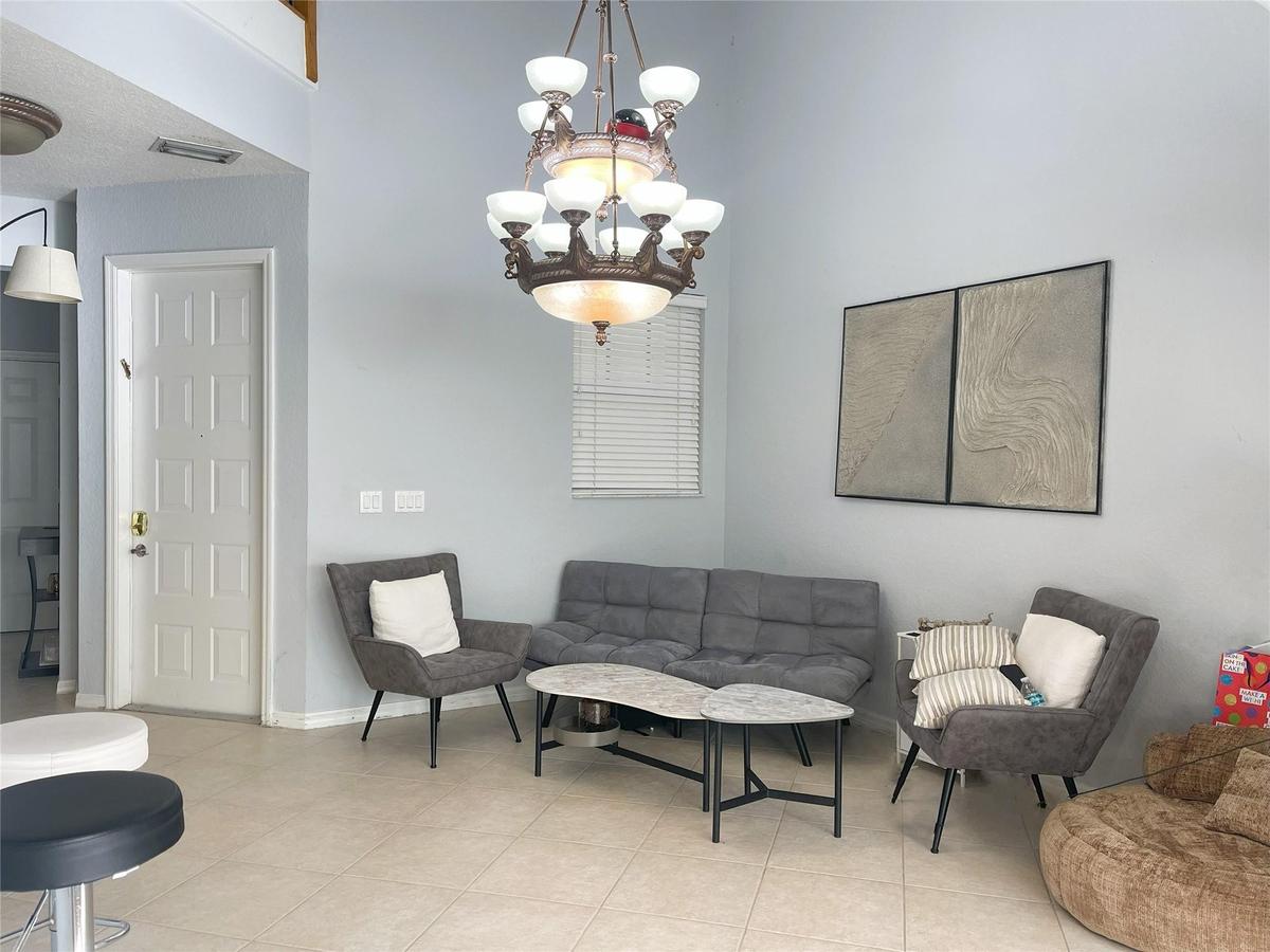 High-ceiling interior featuring tile flooring, a multi-tiered traditional chandelier, and a neutral color palette