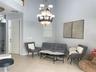 High-ceiling interior featuring tile flooring, a multi-tiered traditional chandelier, and a neutral color palette