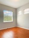 Neutral-toned walls featuring wood-finish flooring, a large dual-pane window, and two elevated transom windows