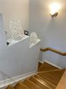Staircase featuring wood treads, a wall-mounted wood handrail, and a wall-mounted light fixture
