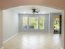 Arched entryway featuring neutral-toned tile flooring, recessed ceiling lighting, a multi-blade ceiling fan, and large windows with grid detailing
