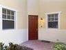 Stucco exterior featuring a dual-tone facade, recessed paneled entry door, brick-paver porch, and multi-pane windows with decorative trim