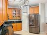 Kitchen featuring wood cabinetry, stone countertops, stainless steel French door refrigerator, glass-front upper cabinet doors, and a rectangular meta