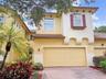 Stucco exterior featuring decorative corbels, a paver driveway, tiled roof accents, and window shutters