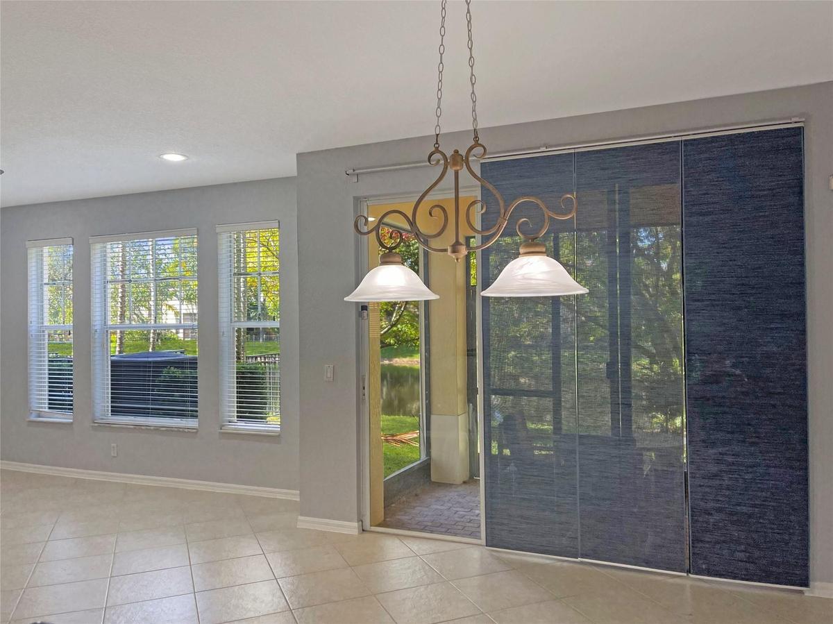 Tile flooring, multi-pane windows, recessed ceiling lighting, decorative dual-bulb pendant fixture, and sliding glass panel doors