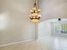 High-ceilinged room featuring a multi-tiered bronze-finish chandelier, arched architectural detailing, tile flooring, and a ceiling fan