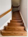 Staircase featuring wood treads and a wall-mounted wooden handrail